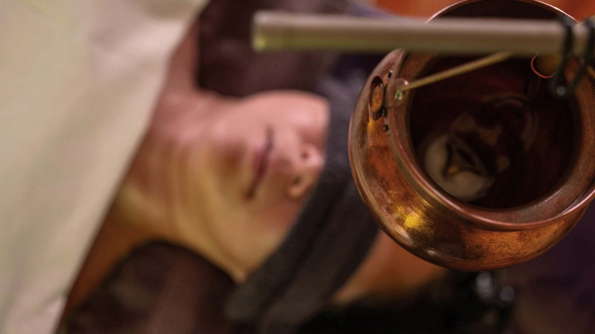 woman getting a shirodhara treatment with warm oil poured on her head