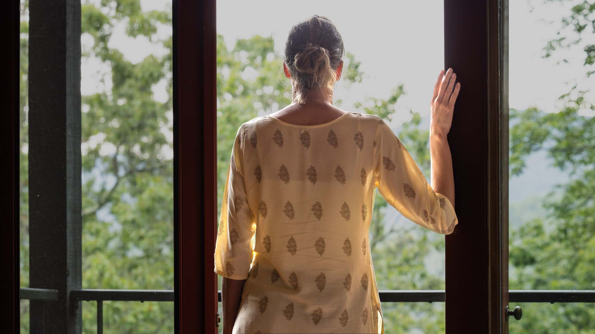 woman at SoHum Mountain Healing Resort, looking out through her window to the mountain scenery