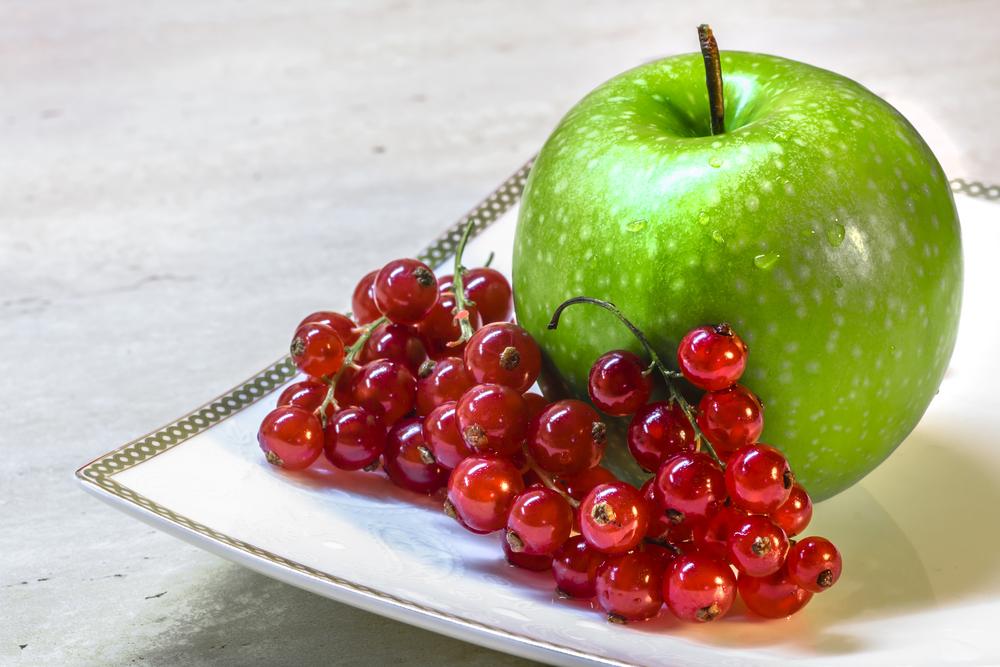 A green apple and berries on a plate.