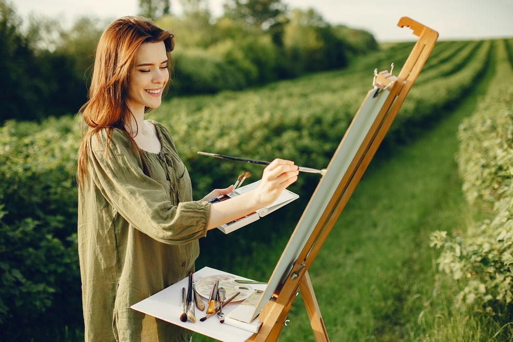 A woman engages in a restorative creative practice outside in nature.