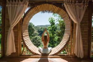 A figure holds a yoga pose in front of a verdant mountain vista.