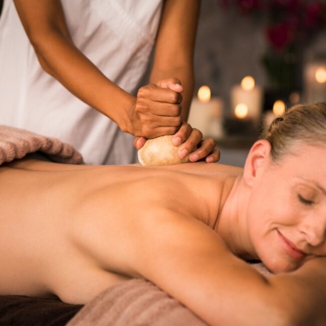A senior woman receives a panchakarma massage during a bodywork session.