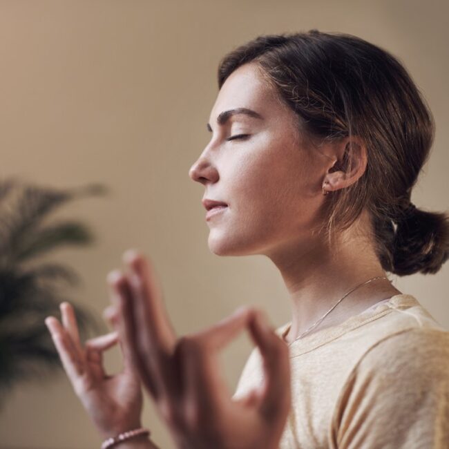 A woman meditates with eyes closed.