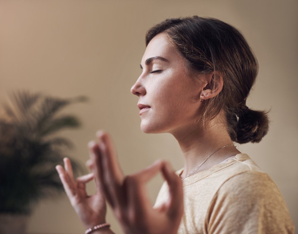A woman meditates with eyes closed.