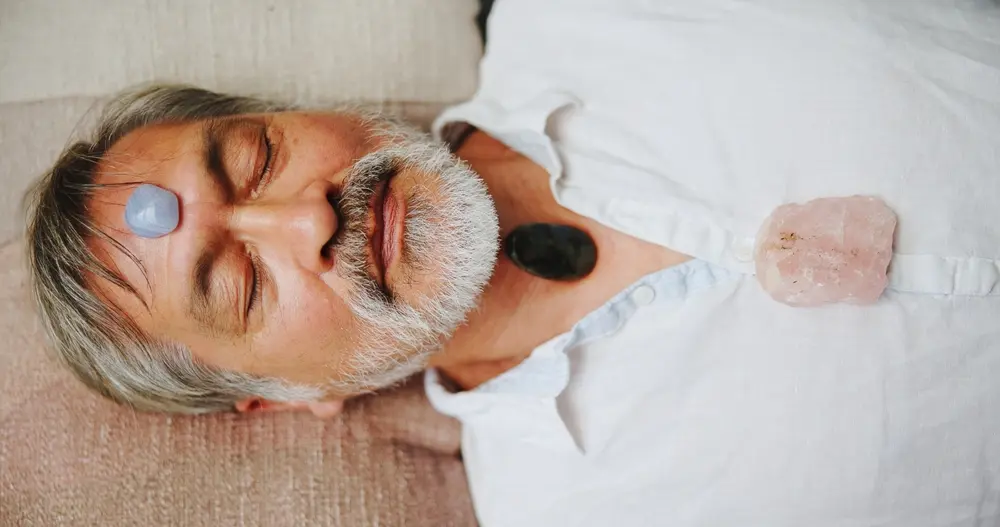 An older man participates in crystal meditation.