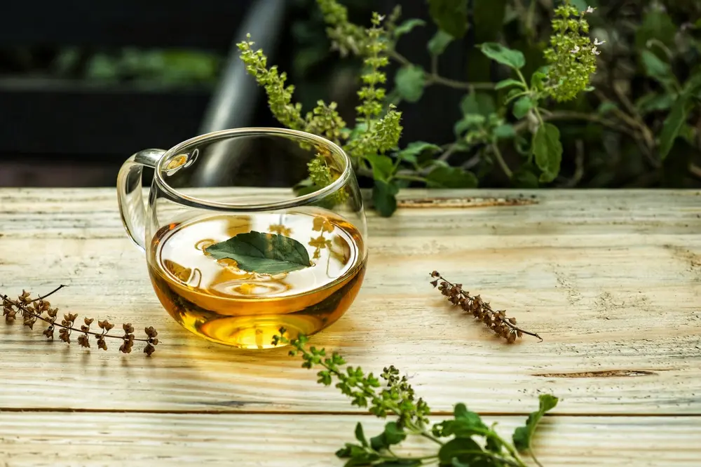 Tulsi tea in a glass mug on a wooden table.