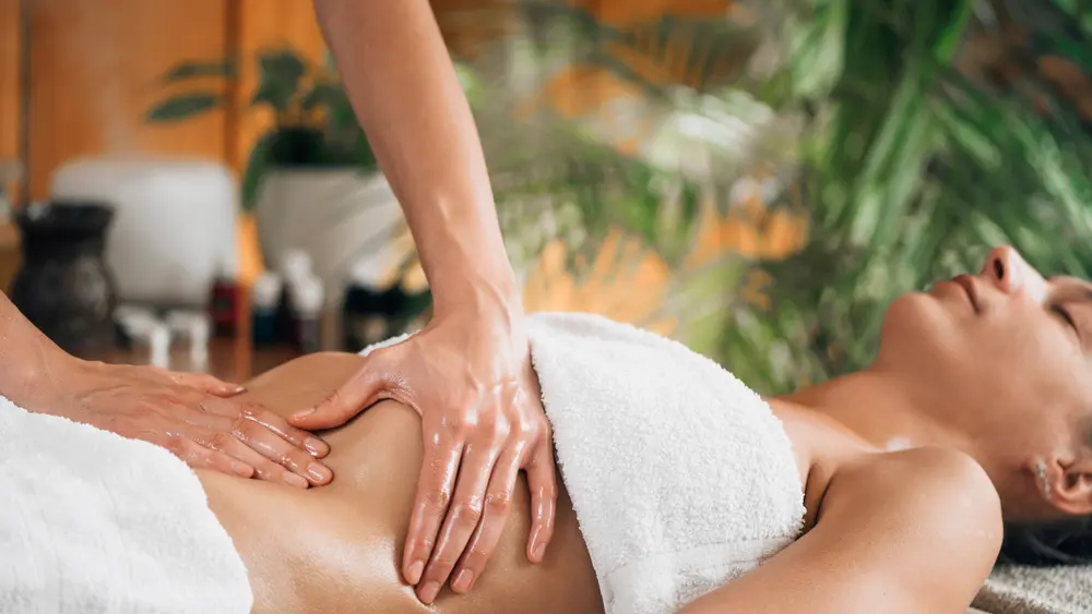 A woman with closed eyes receiving an Ayurvedic oil massage.