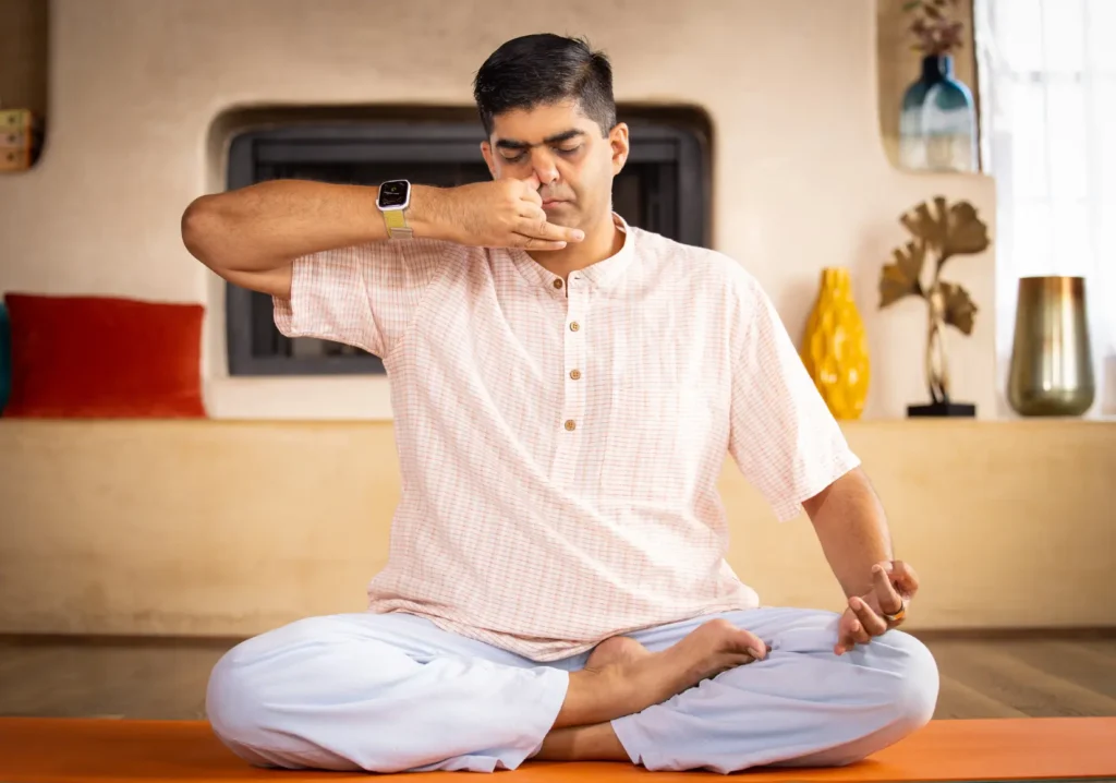 A man sitting practicing alternate nostril breathing