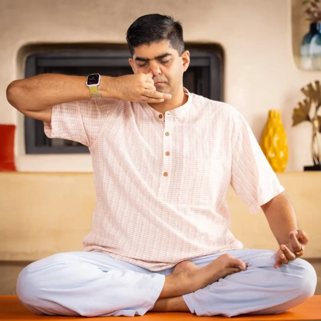 A man sitting practicing alternate nostril breathing
