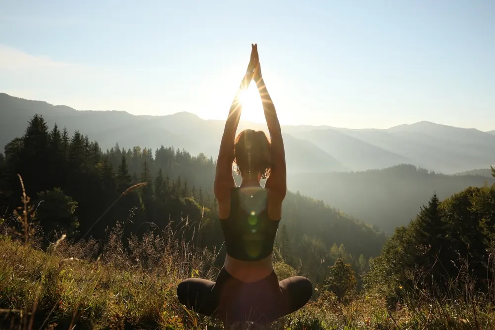 A woman practicing mindfulness grounding techniques in the mountains.