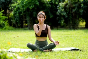 A woman sitting outdoors practicing alternate nostril breathing