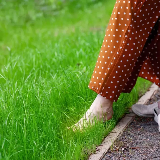 A woman walking barefoot in the grass as a grounding practice.