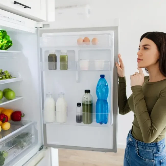 A woman in front of a fridge choosing meal ingredients